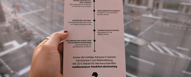 Eine Hand hält einen Flyer vor dem Hintergrund einer leeren Straße.