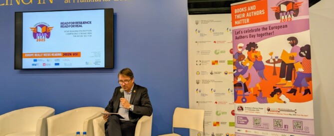 Ein Mann sitzt vor einem blauen Hintergrund und spricht in ein Mikrofon.