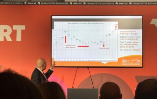 Auf einem Bildschirm wird eine Grafik dargestellt. Ein mann steht davor und zeigt darauf.