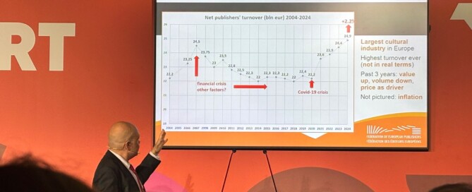 Auf einem Bildschirm wird eine Grafik dargestellt. Ein mann steht davor und zeigt darauf.